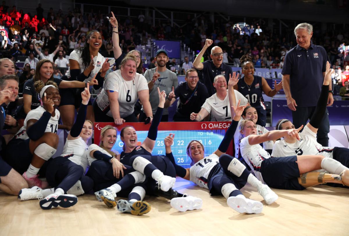 Female sitting volleyball players are celebrating in front of a scoreboard at the Paris 2024 Paralympic Games