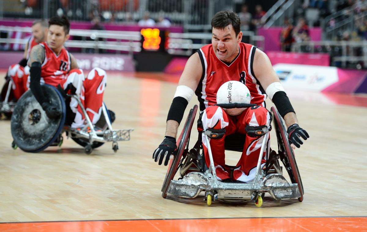 A male athlete is carrying a white ball during a wheelchair rugby competition