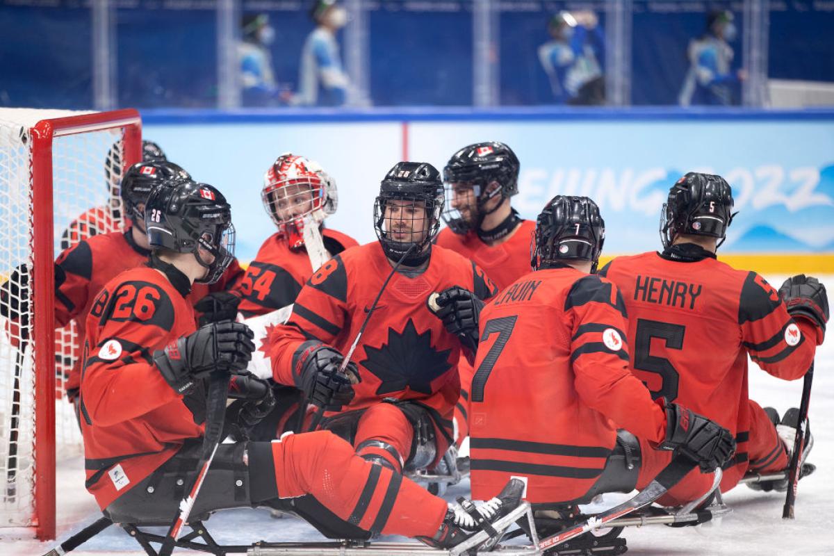 A group of Canadian Para ice hockey players gathering on the rink