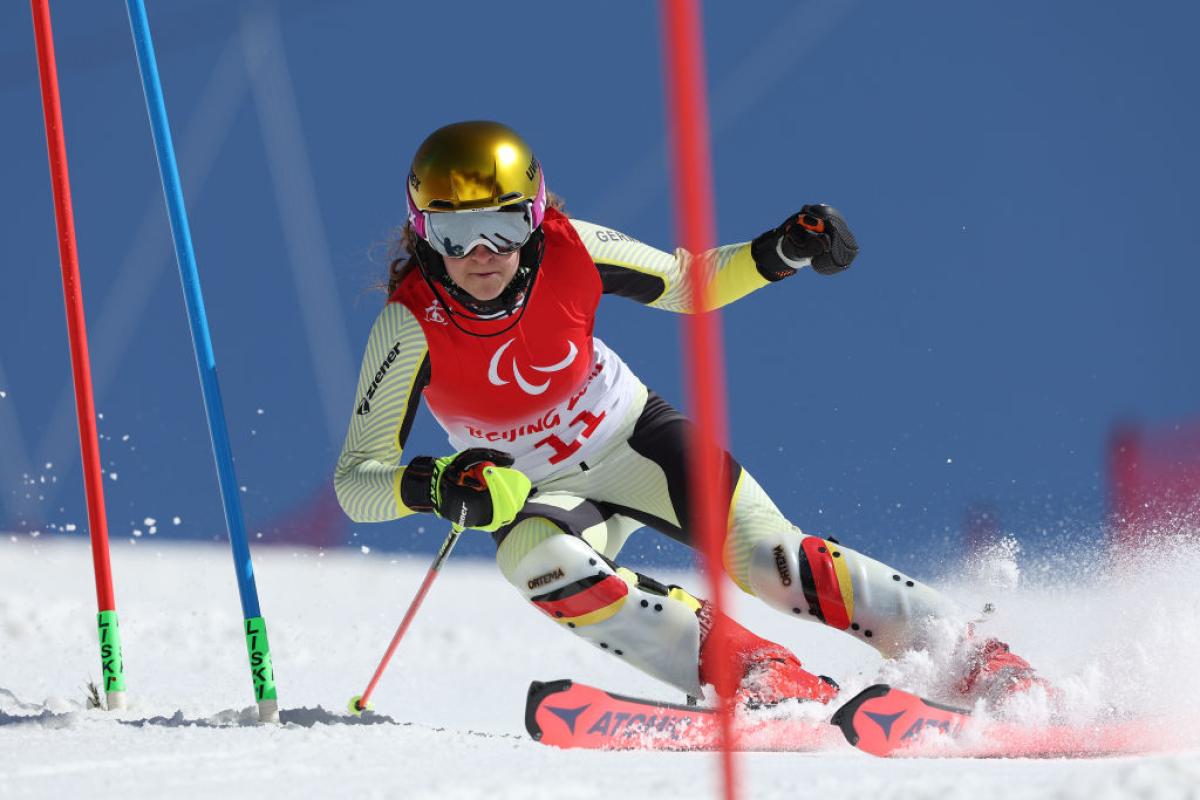 A female athlete skiing downhill between poles