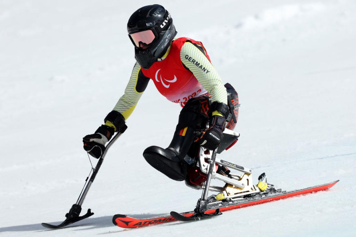 A woman races on snow in a sit ski