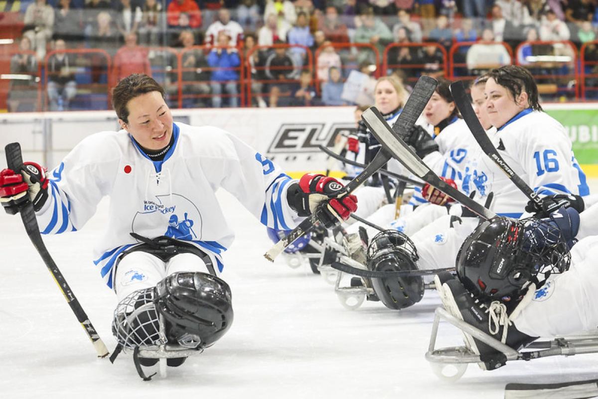 A female Para ice hockey player parading in front of her teammates