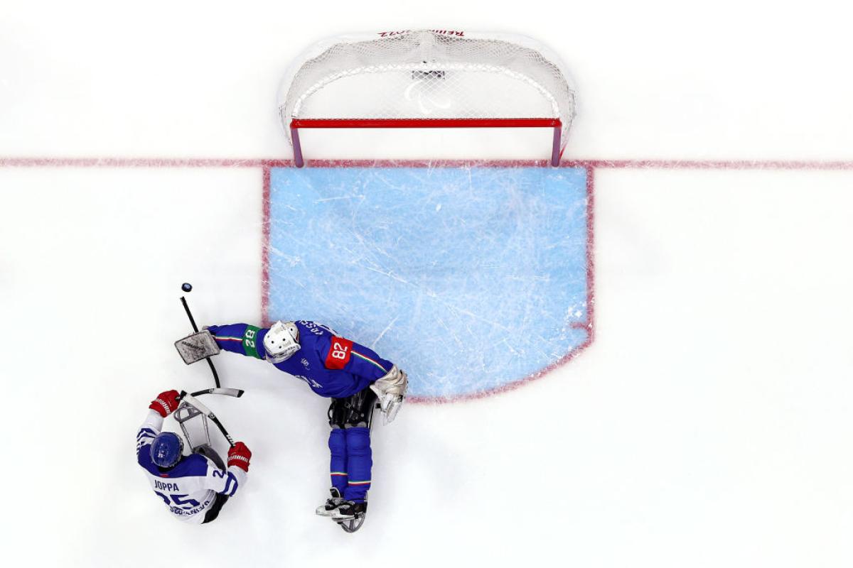 An aerial view of a Para ice hockey player scoring in front of a goaltender