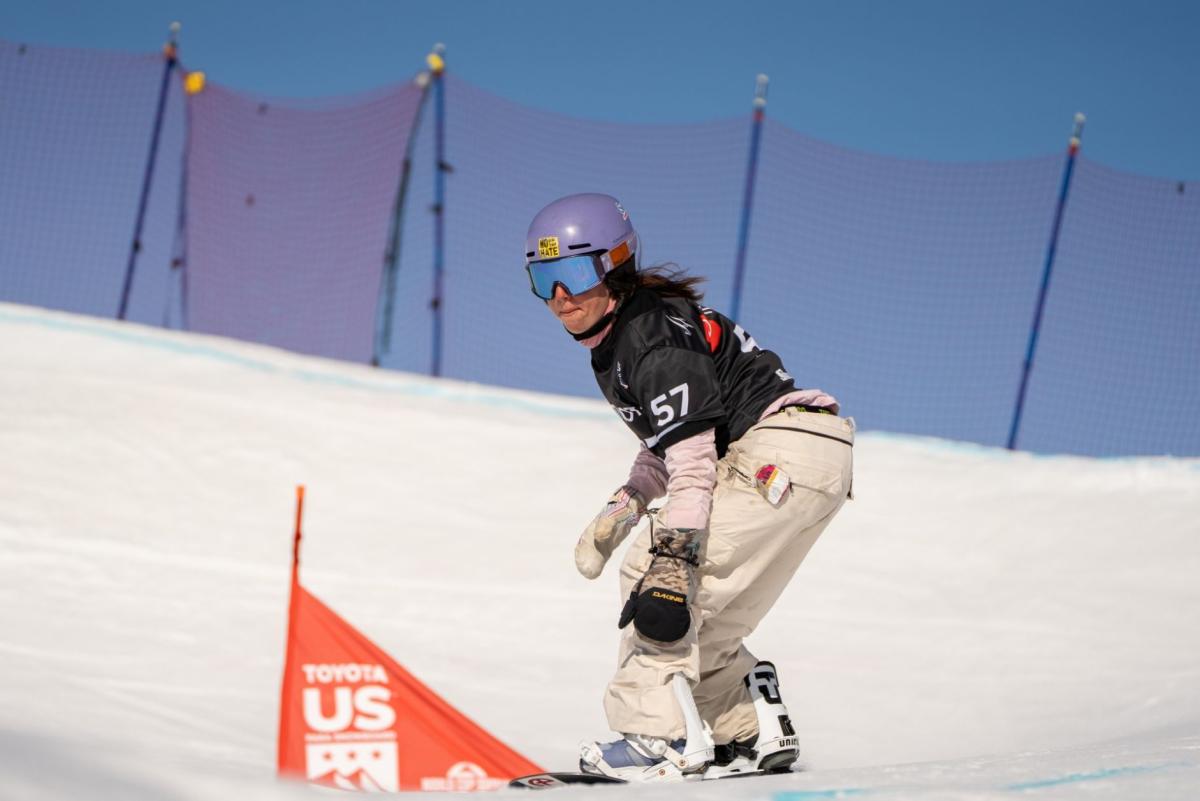 A female Para snowboarder competing on the course, while making a turn