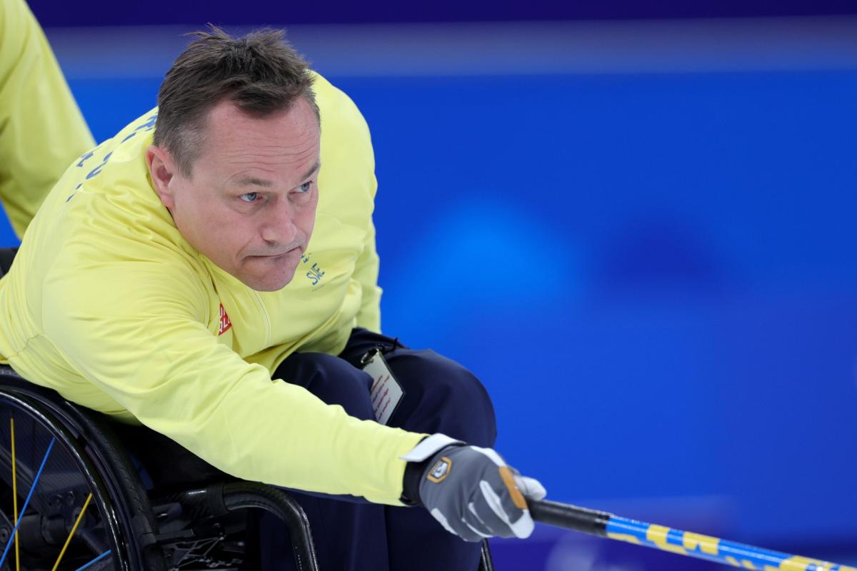 A male wheelchair curler releasing the stone with the stick