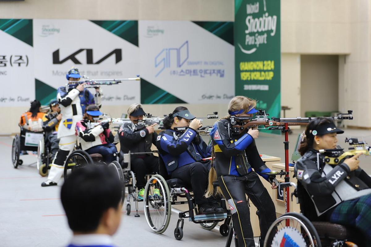 A group of female shooting Para sport athletes competing in a shooting range