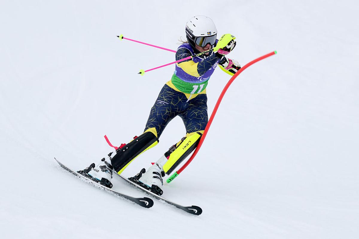 Female skier brushes red slalom pole