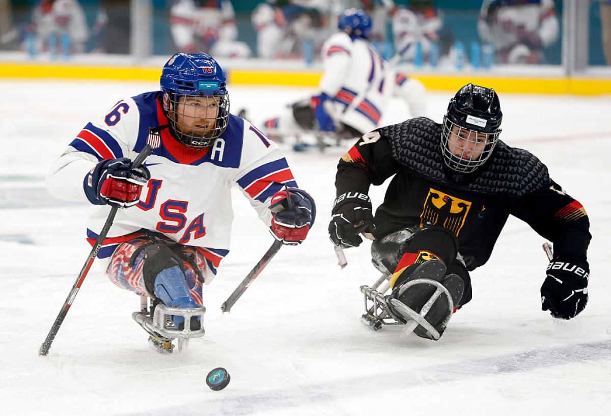 A USA and a German Para ice hockey player going for the puck