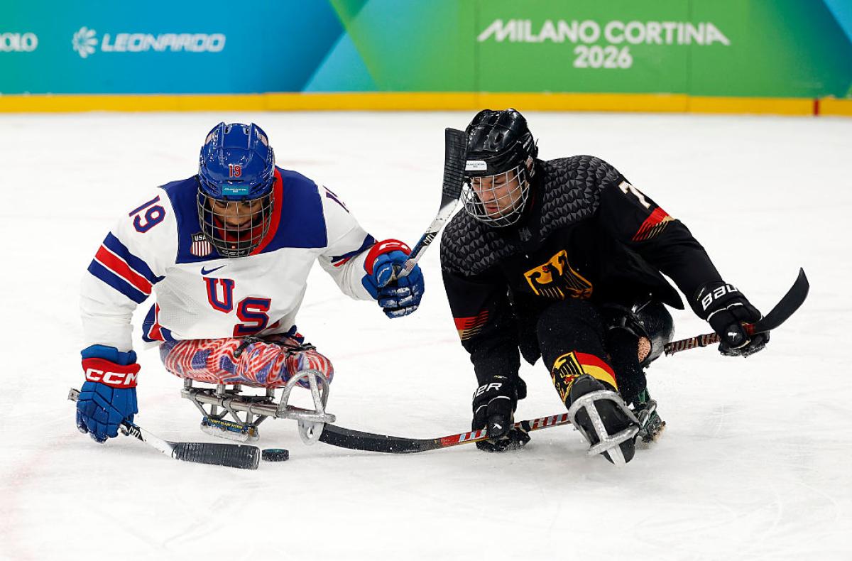 A German and a USA Para ice hockey players going for the puck