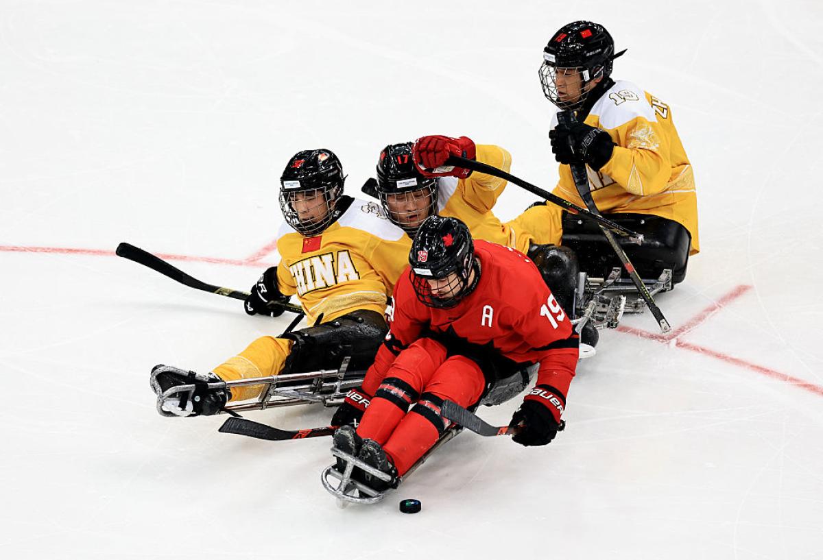 A Canadian Para ice hockey player followed by three Chinese players