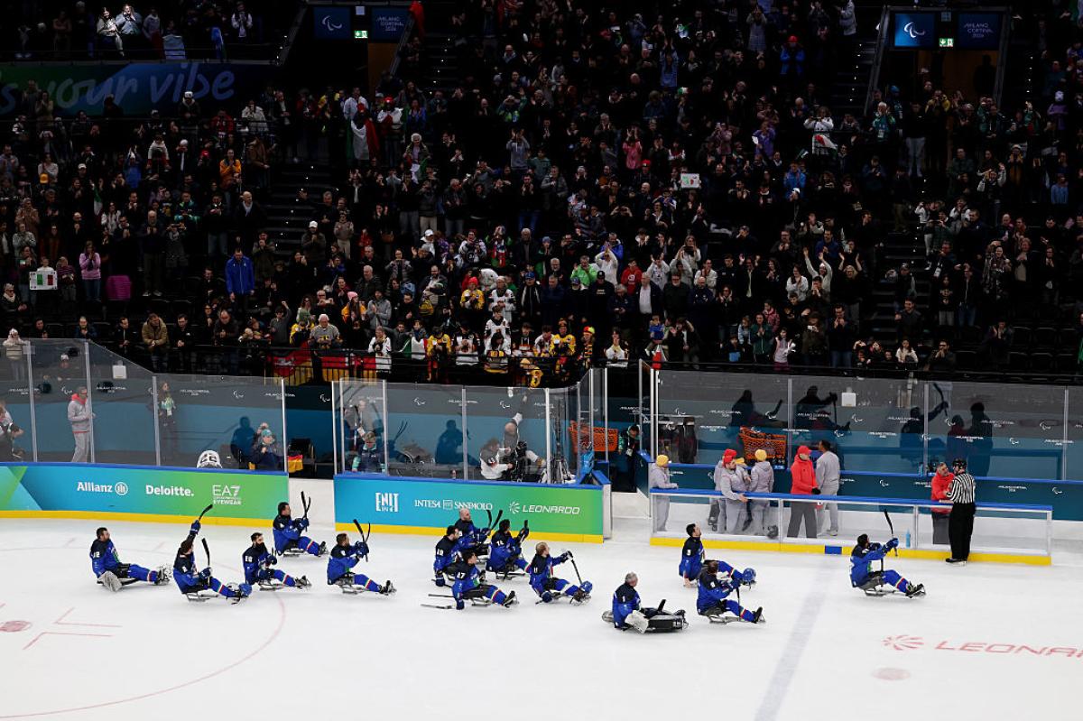 Italian Para ice hockey players saluting the crowd in an arena