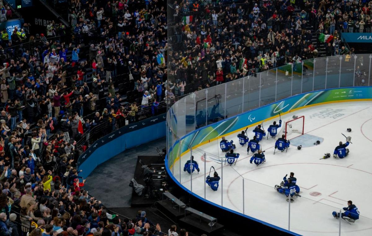 Fans in the stands clapping to the Italian Para ice hockey team on ice