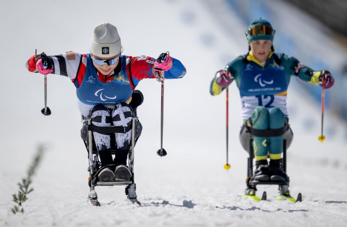 Two female sit-skiers race side by side