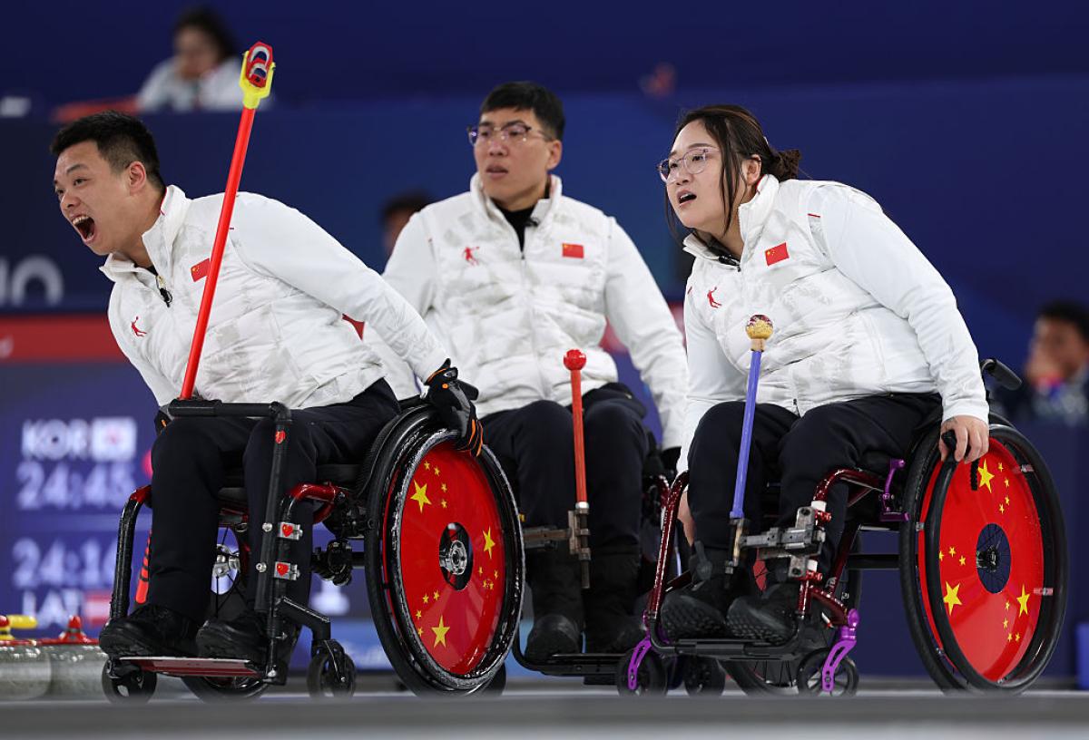 Three wheelchair curling athletes are in competition