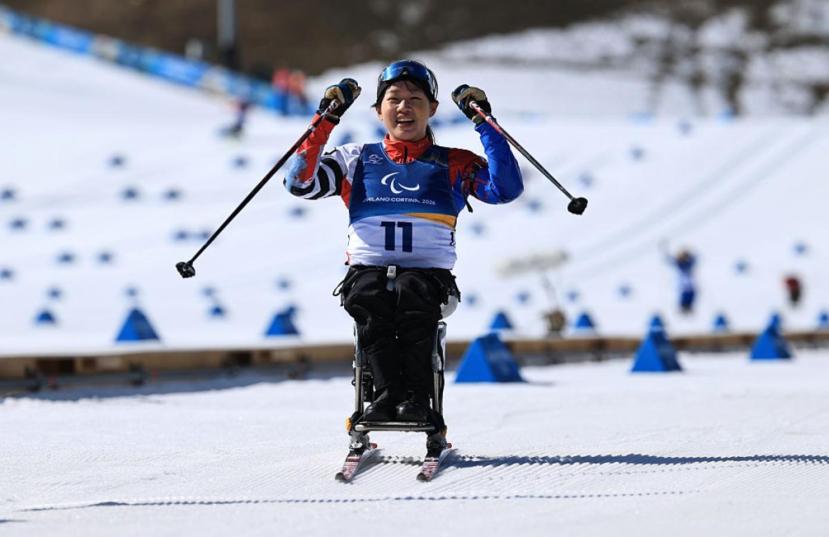 A female sit-ski athlete smiles 