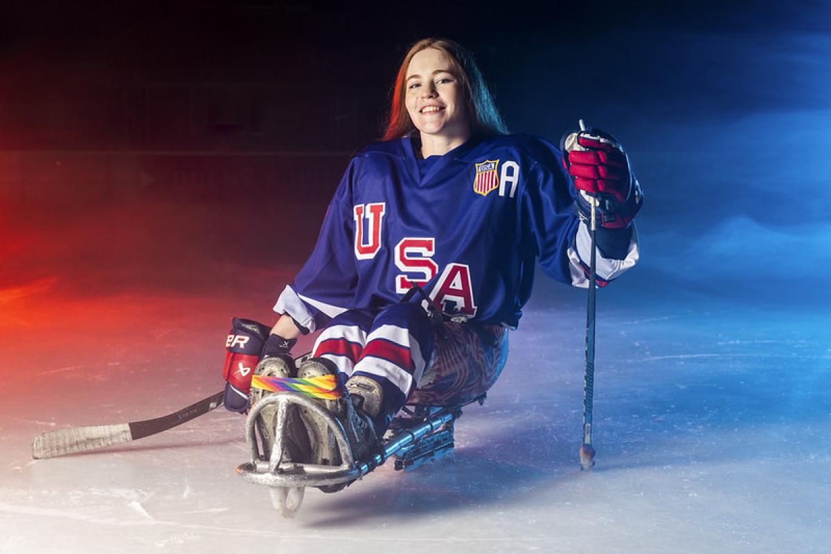 A female Para ice hockey player on ice smiling while posing for a picture