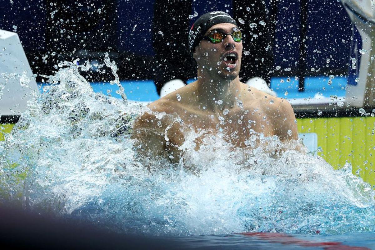 A swimmer celebrating splashing water from inside the pool