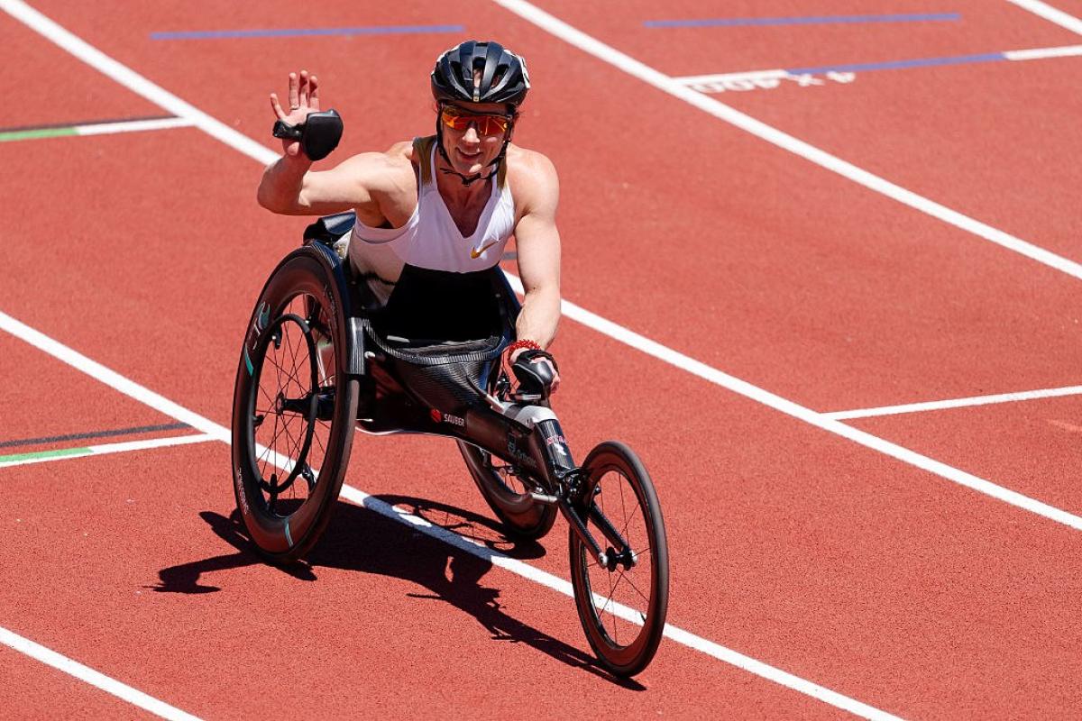 A female wheelchair racer waving from the track