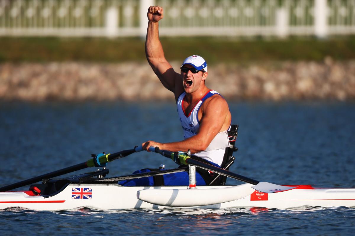 British male rower holds fist in air in celebration