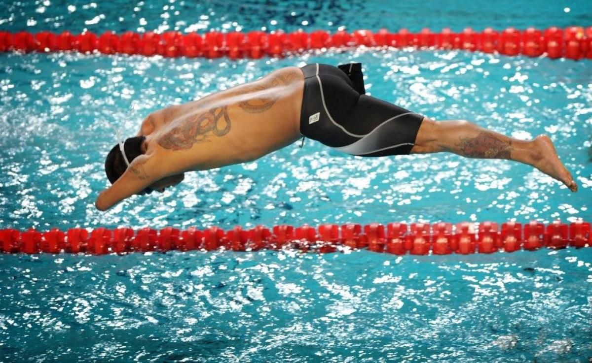 Swimmer starts a race from the start block jumping in the water.