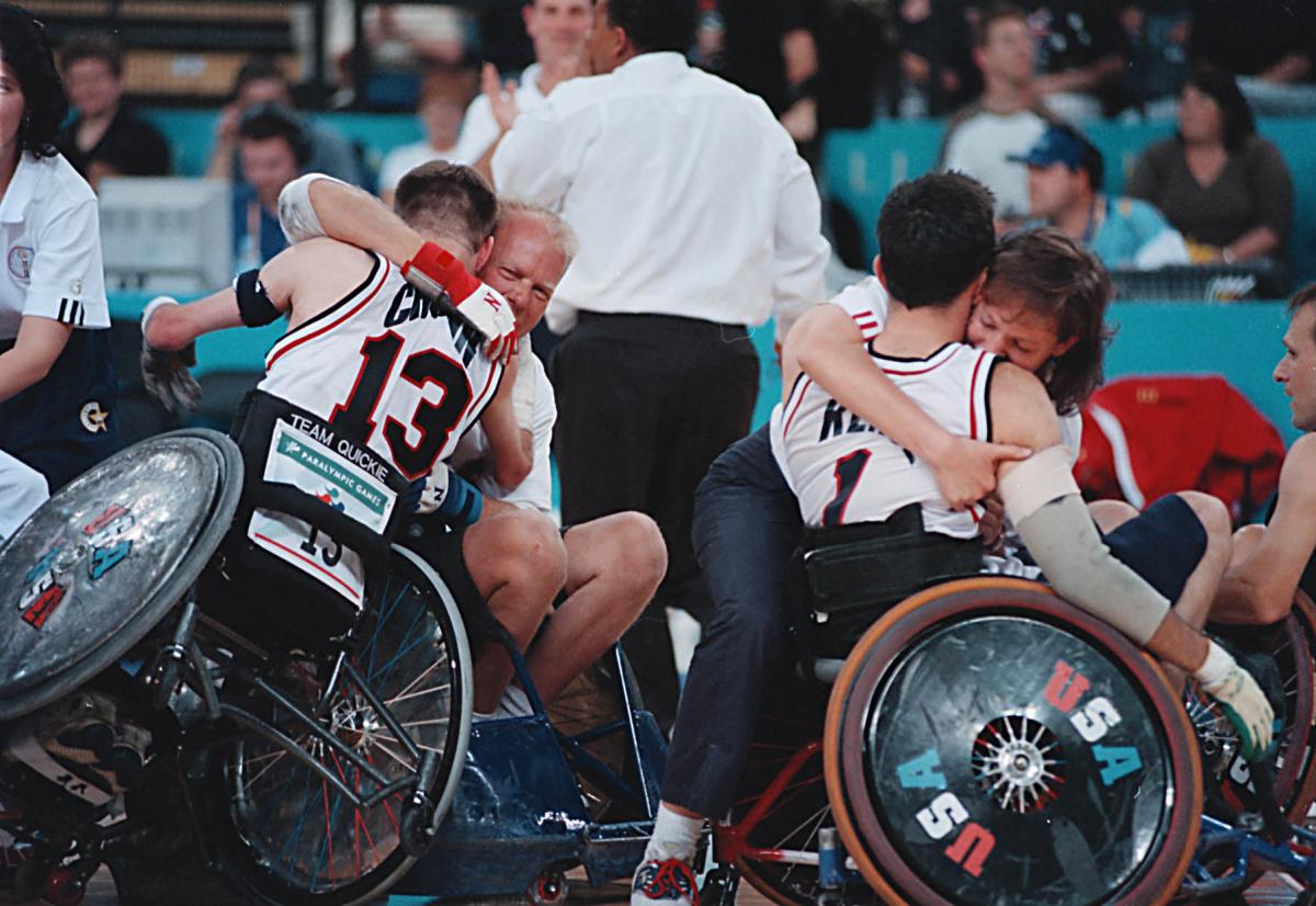 USA Wheelchair Rugby players celebrating their victory A picture of a man in a wheelchair and a girl celebrating a victory.