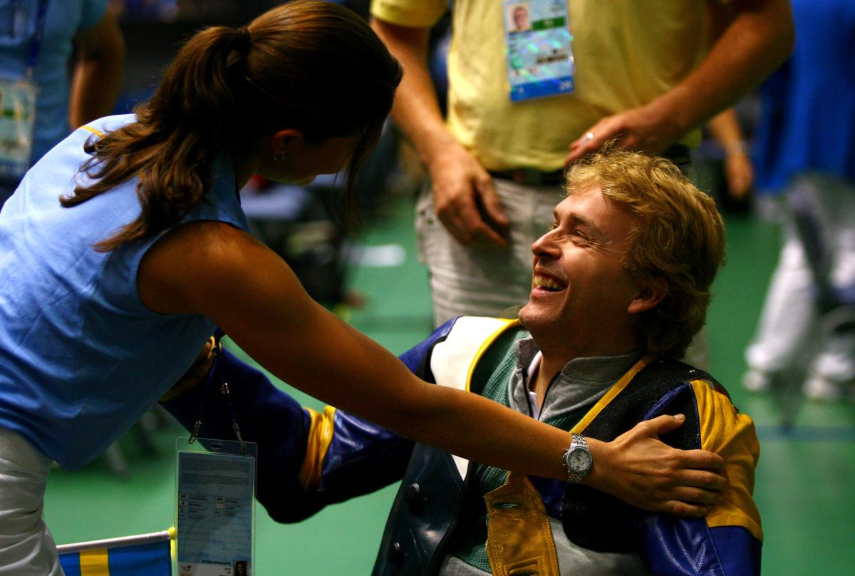Jonas Jacobsson celebrating with his teammate after winning the Men's R7-50m Free Rifle 3x40-SH1 Final Shooting event during the day four of the 2008 Paralympic Games. A picture of a man in a wheelchair congratulated by a woman