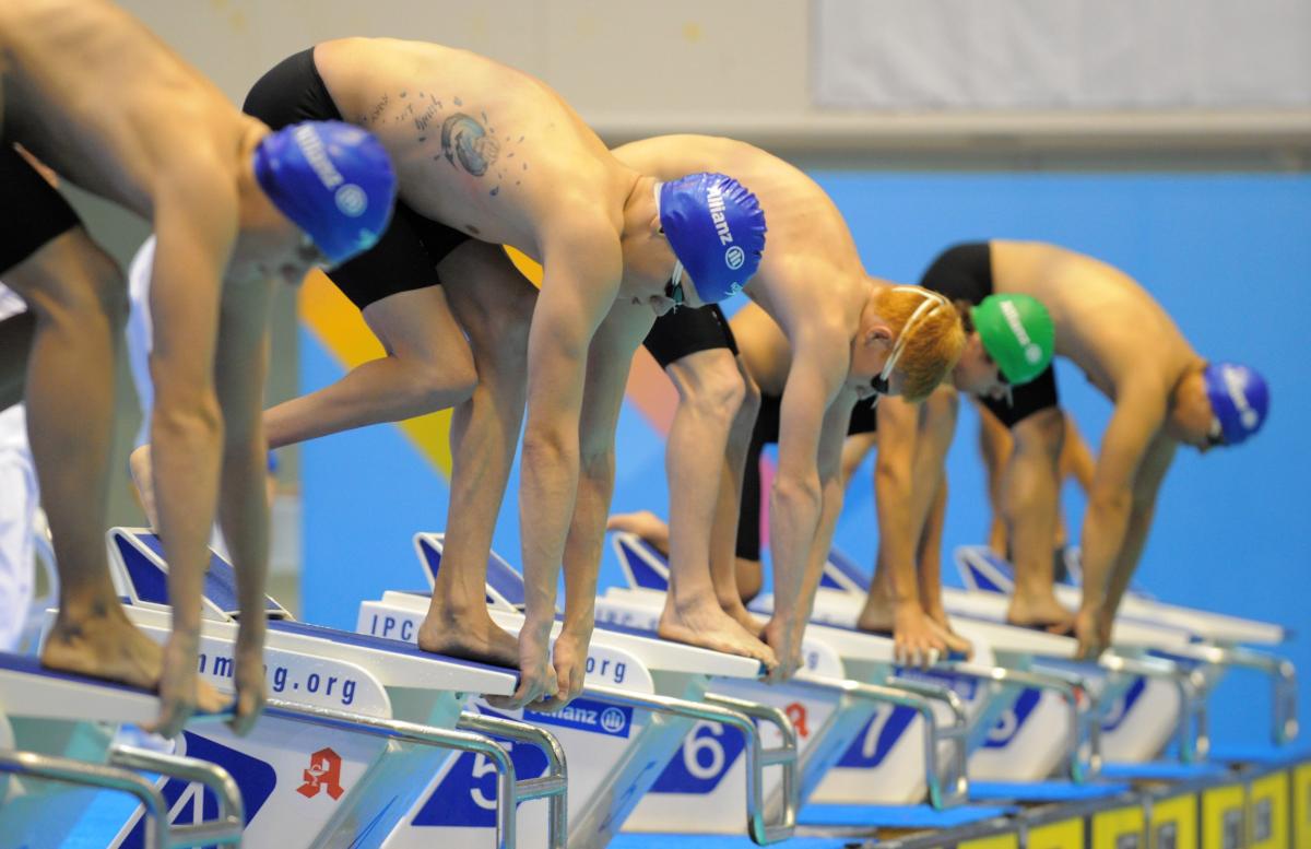 A picture of men ready to jump in a pool for a race