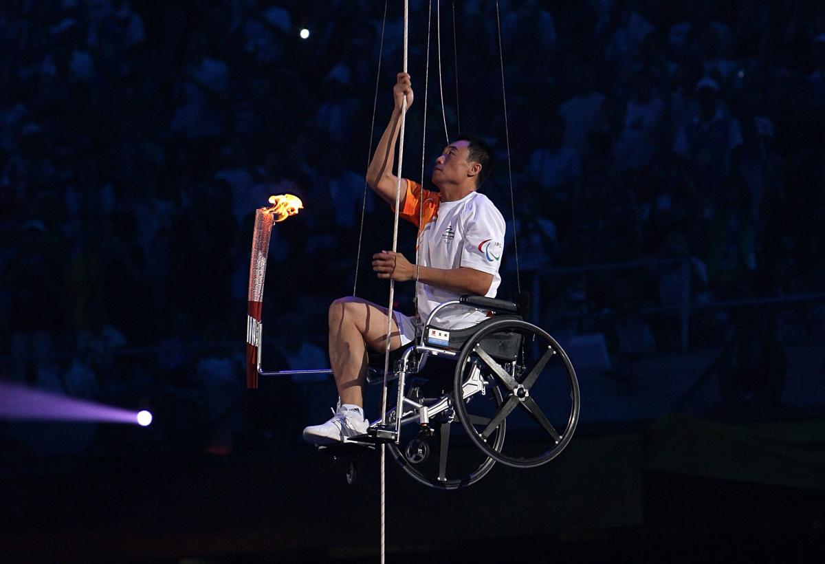 A picture of a man in wheelchair climbing with a torch