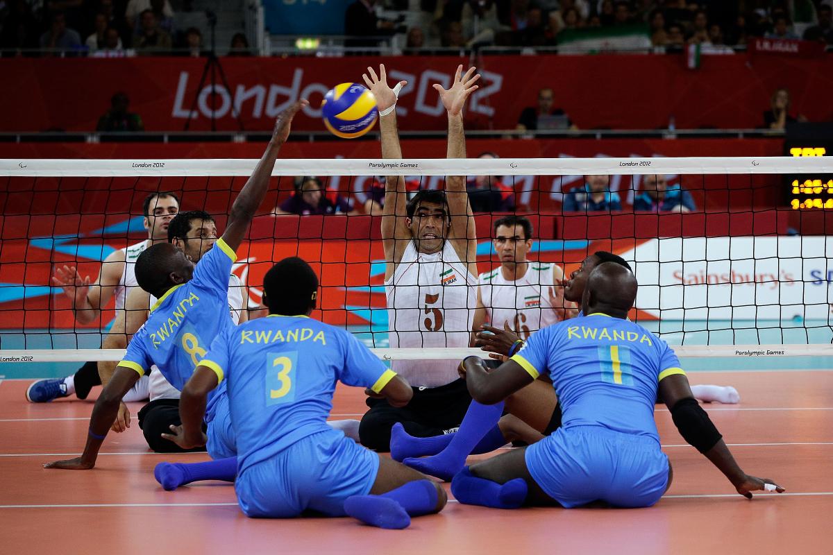 A picture of mens sit down on the ground and playing volleyball.