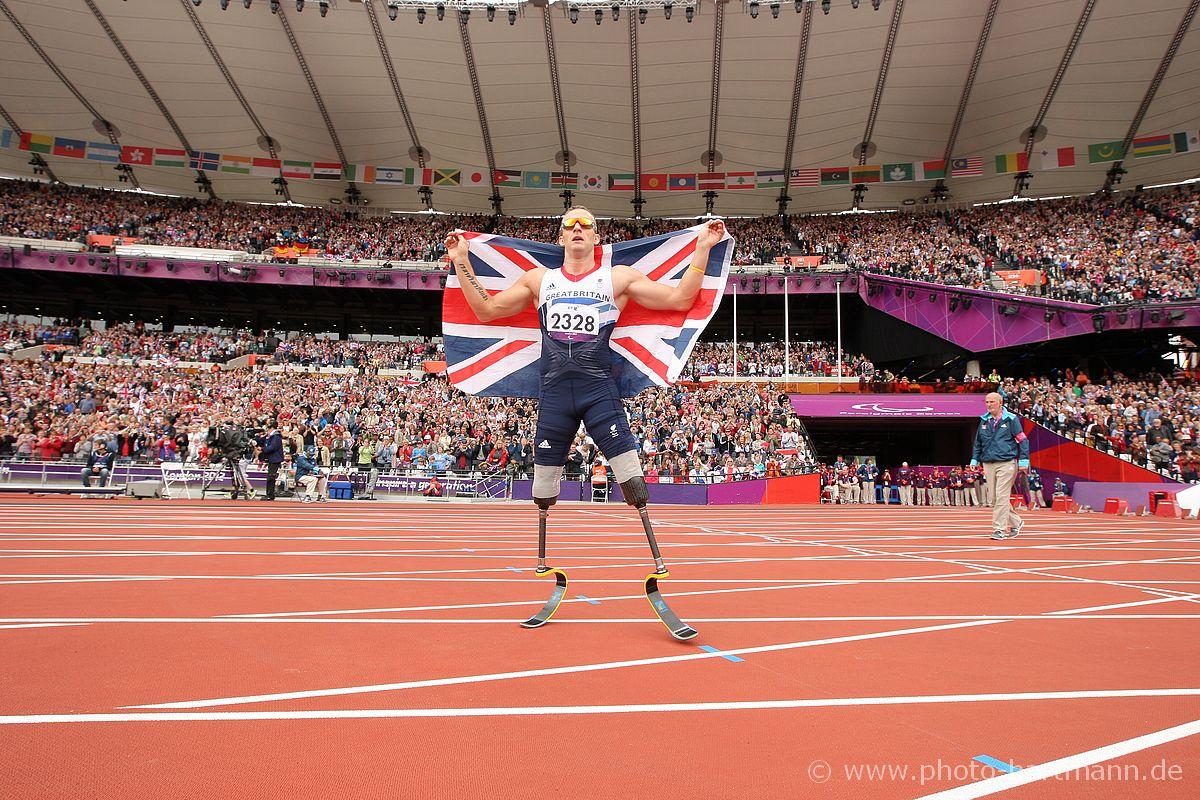 A picture of a man celebrating his victory wearing a flag of Great Britain