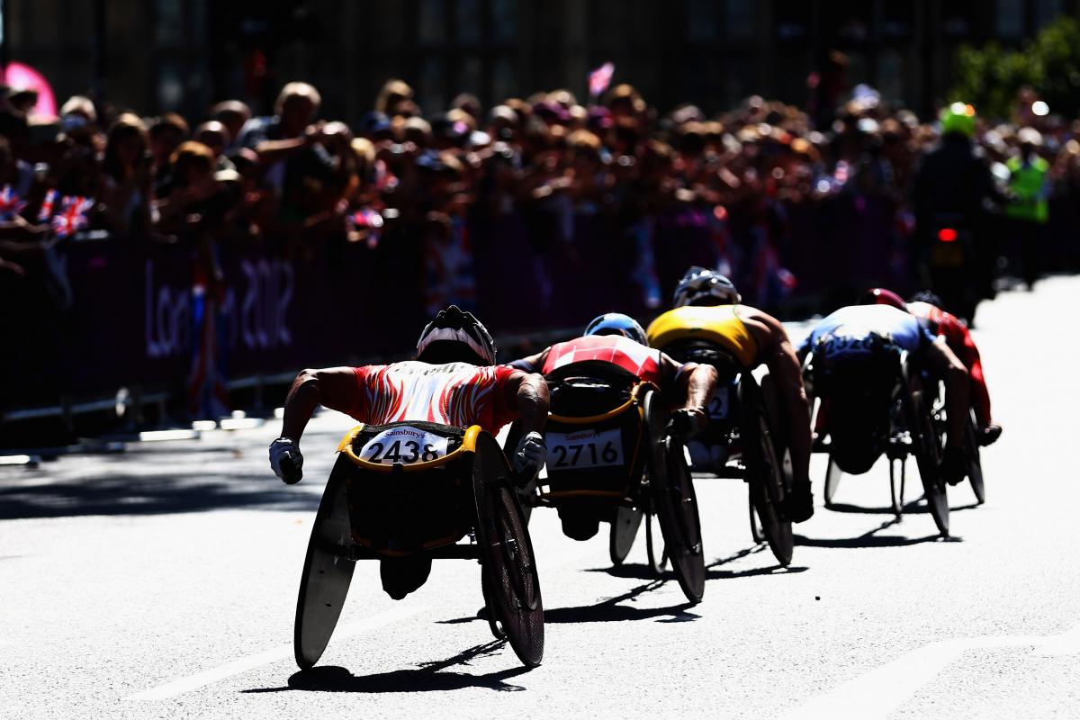 London 2012 Marathon group of men in racing wheelchairs pass spectators