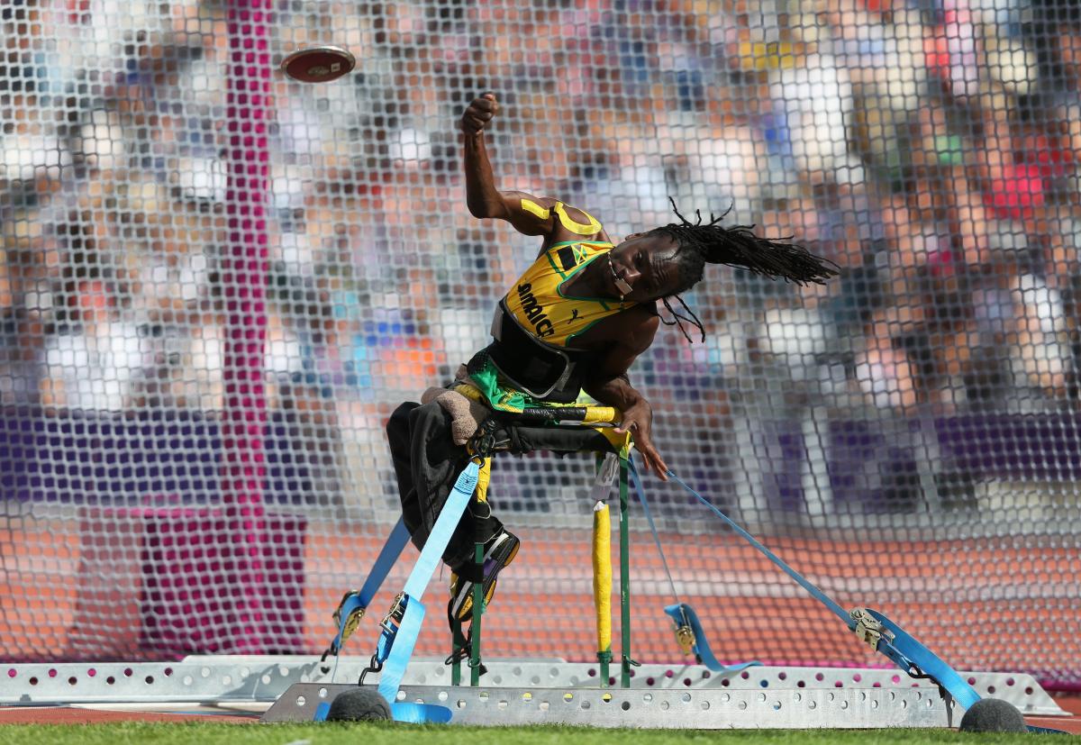 A picture of a man sit down and throwing a discus