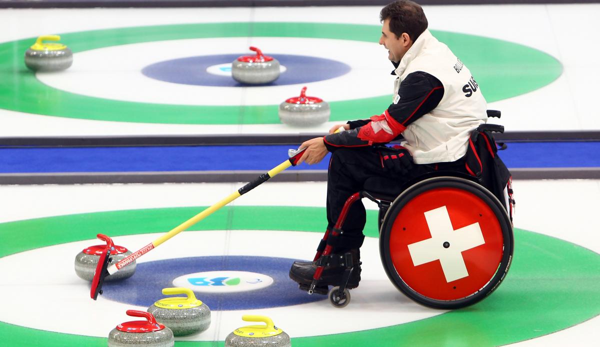 A picture of a man in a wheelchair playing Curling