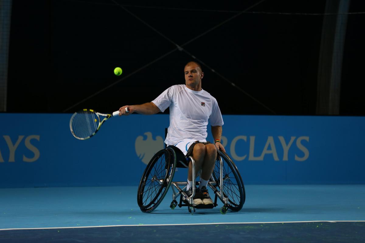 A picture of a man in a wheelchair playing tennis.