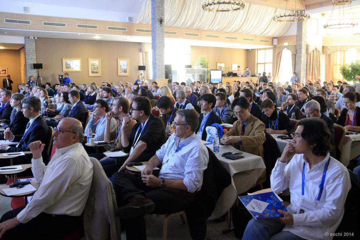 A picture of room fill in by several attendees listening a conference