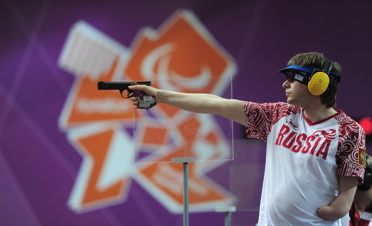 Sergey Malyshev of Russia, wearing glasses, a visor and ear protection shoots his Mixed P3-25m Pistol at an indoor range at The Royal Artillery Barracks