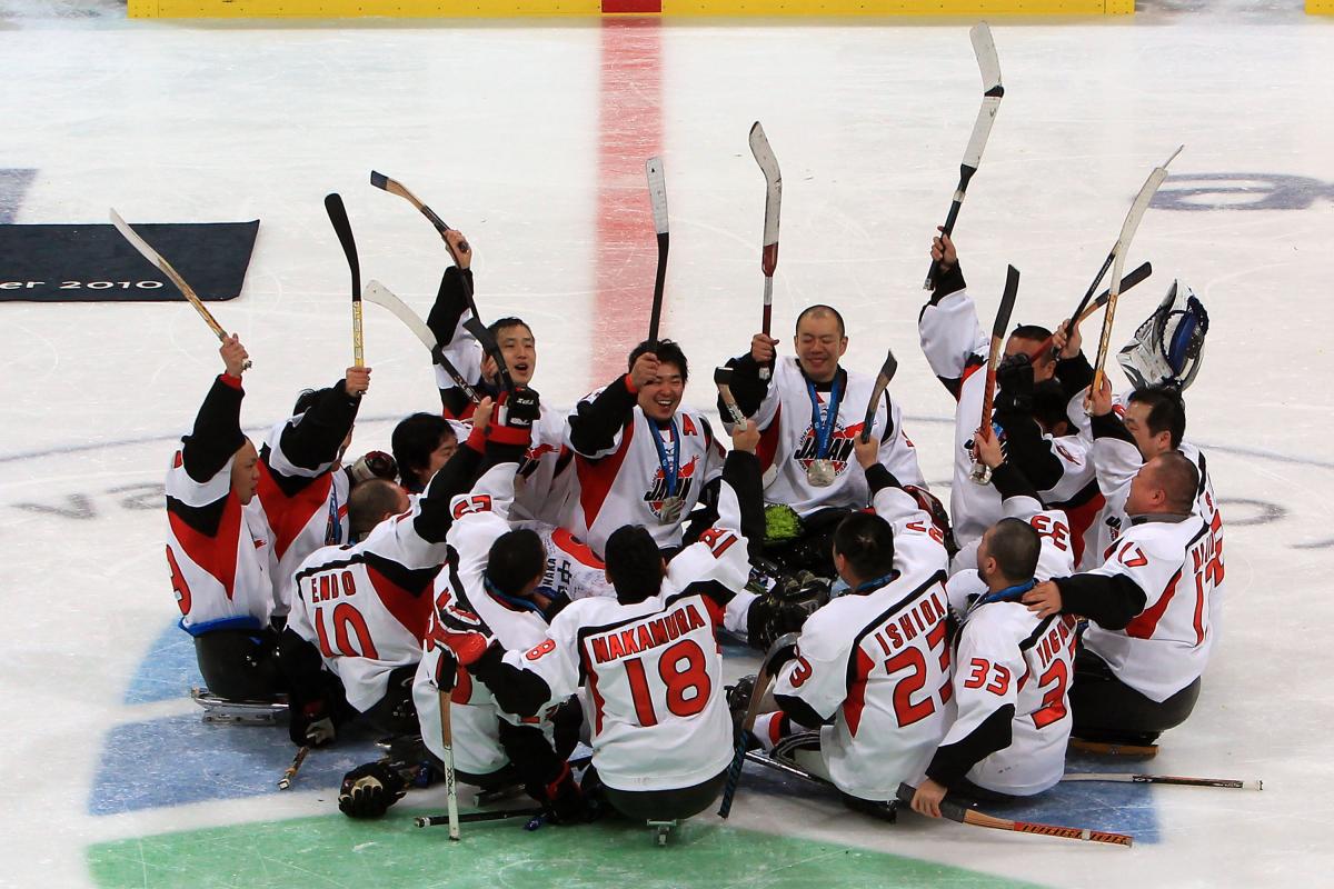 Japan Ice Sledge Hockey Team A picture of men playing sledge hockey celebrating their victory