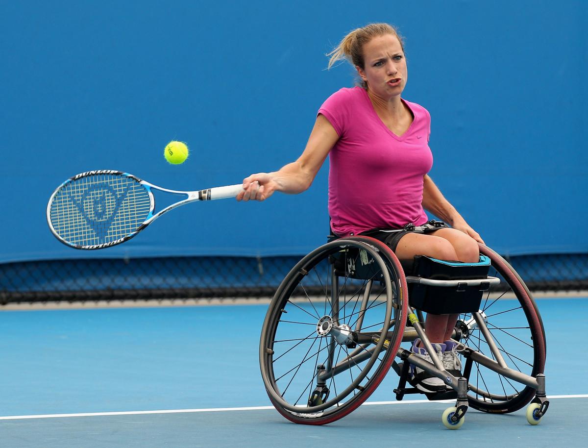 Female wheelchair tennis player in action on a blue court