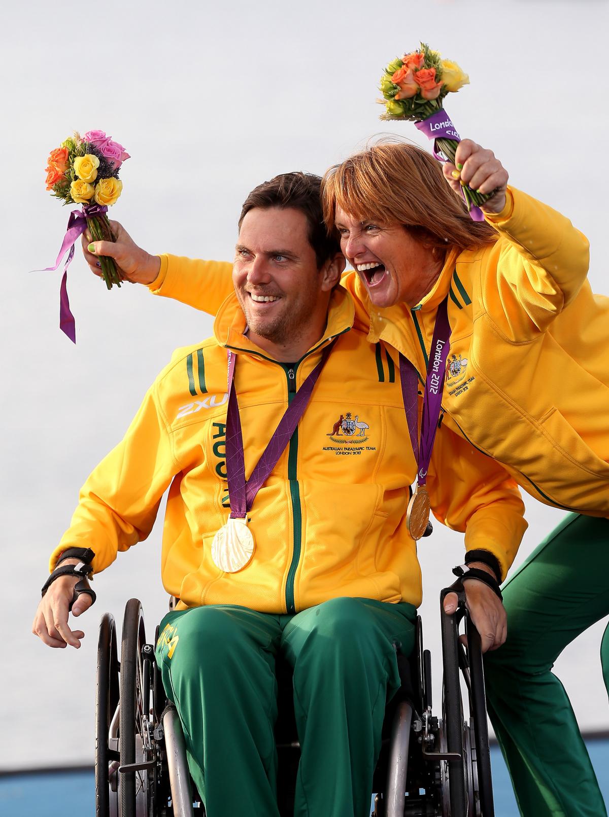 A picture of a man in a wheelchair and woman celebrating their victory with a gold medal around their necks