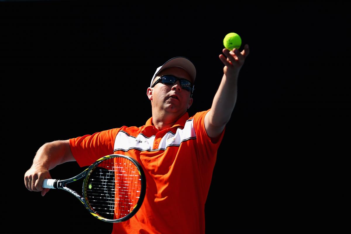 Ronald Vink A picture of a man in a wheelchair serving during a tennis match