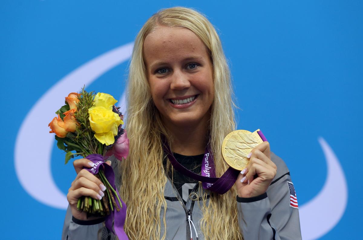 A picture foa a blonde woman showing her gold medal hanging around her neck