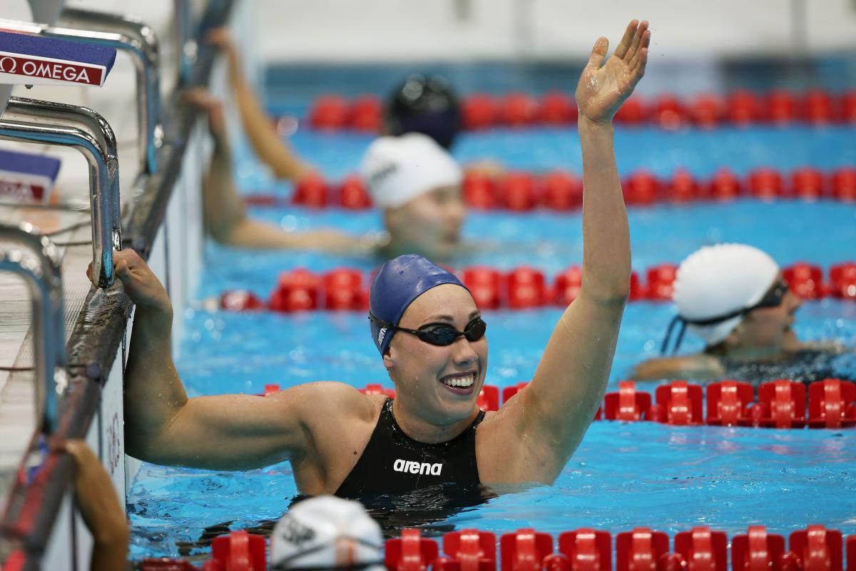 A picture of a woman in the pool with her hand up