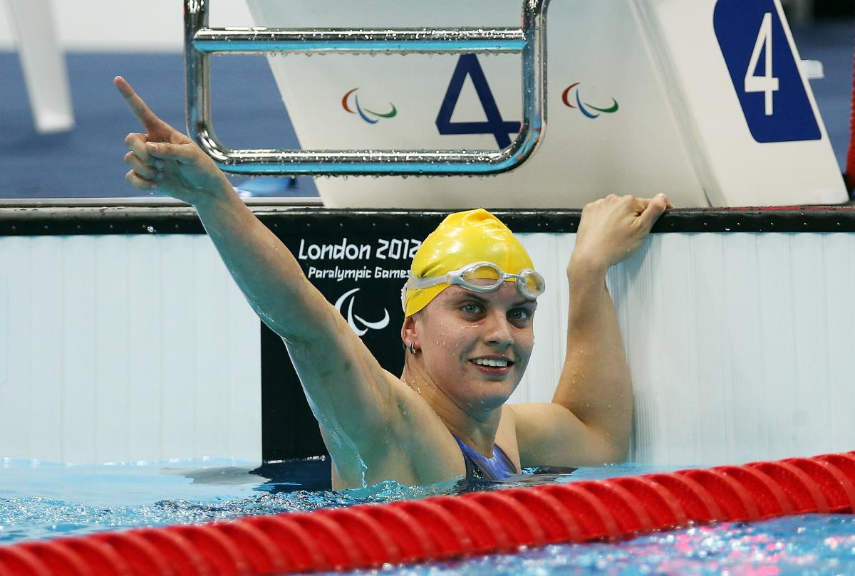 A picture of a woman in the pool holding her hand up