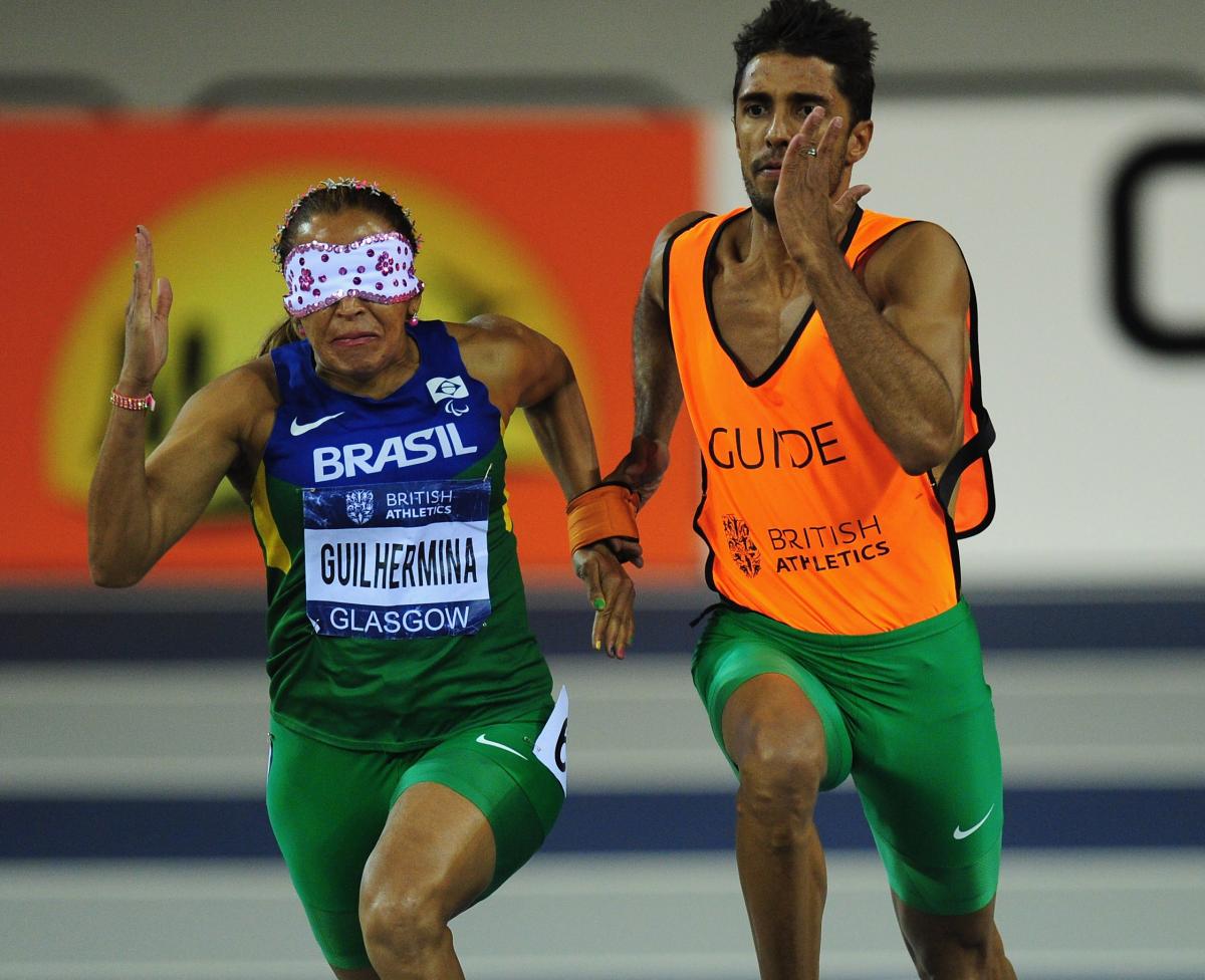 A picture of a blind woman running with her guide during an athletics race.