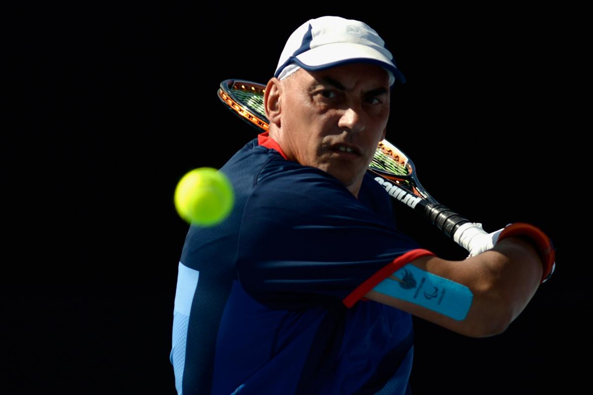 A picture of a man in a wheelchair playing a backhand during a wheelchair tennis match