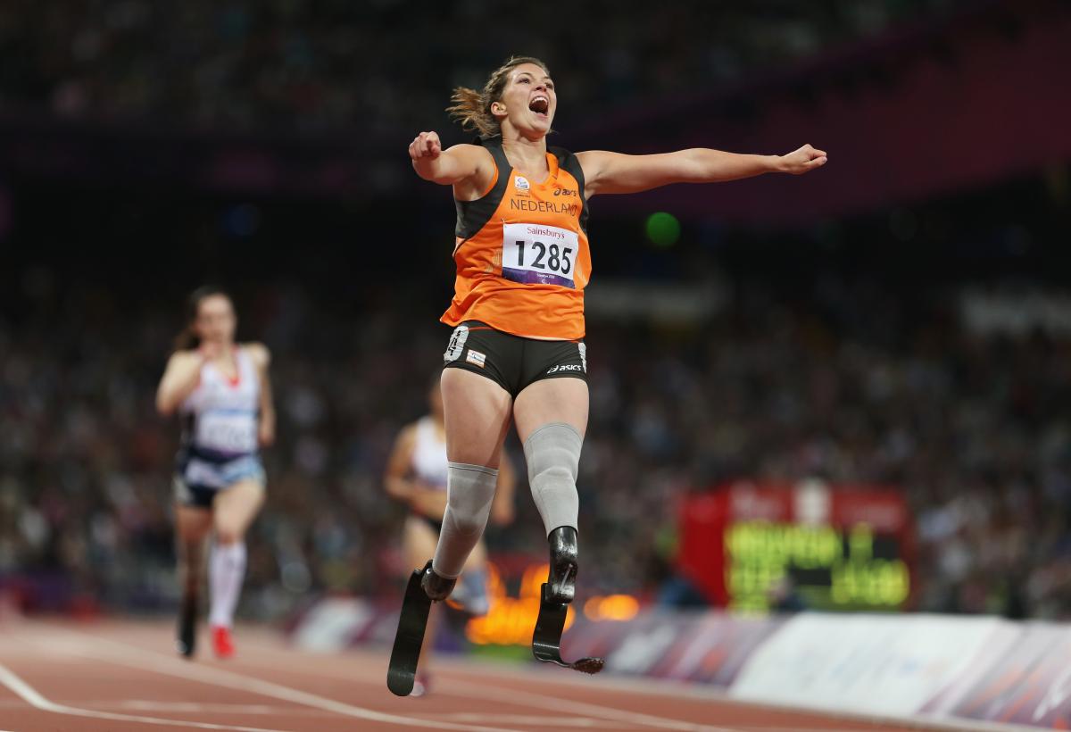 A picture of a woman on the running track celebrating with her hands spread