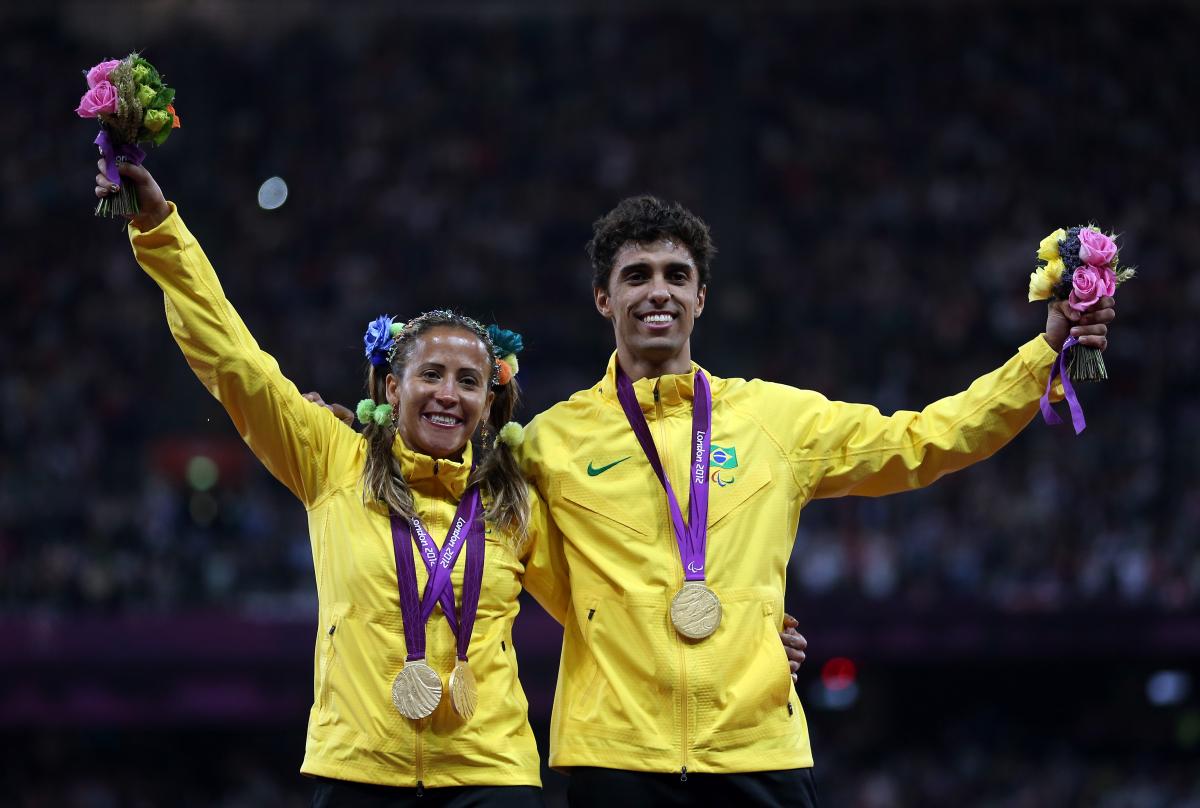 A picture of a woman and a man on a podium with medals around their neck
