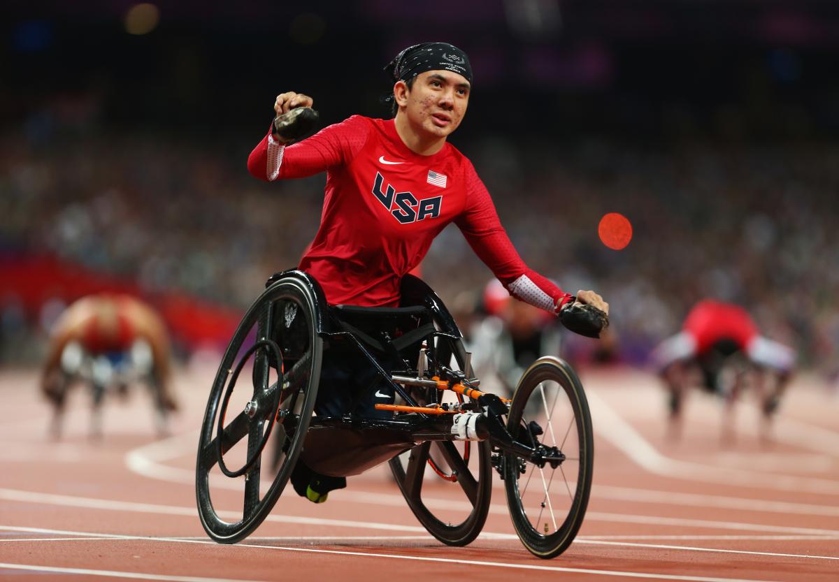 A picture of a man in a wheelchair celebrates after crossing a finish line