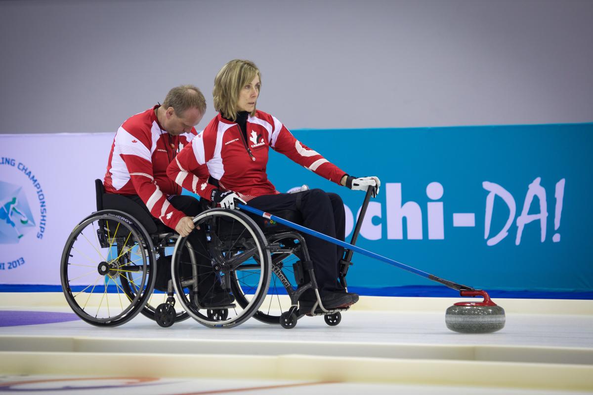 Canada Wheelchair Curling A picture of 2 person in wheelchairs playing curling