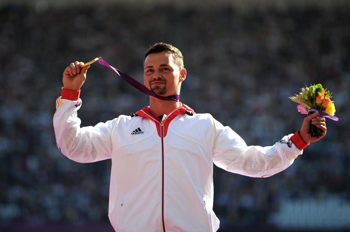 A picture of a man on a podium with a medal around his neck